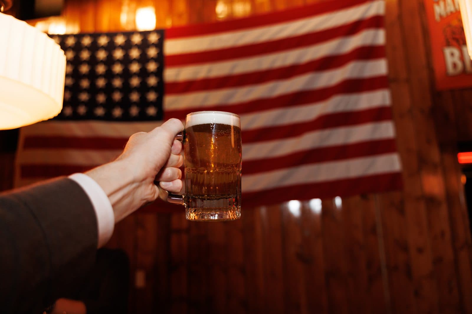 A raised mug of beer in front of the flag at PubKey