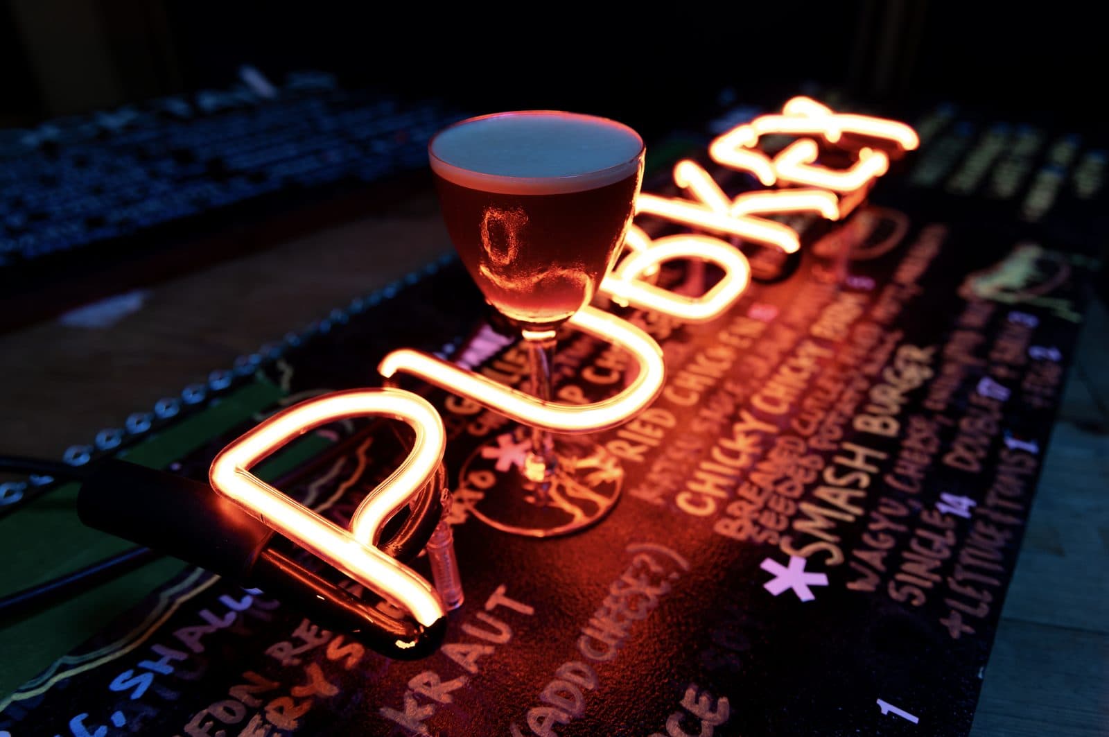A cocktail resting on the neon PubKey sign