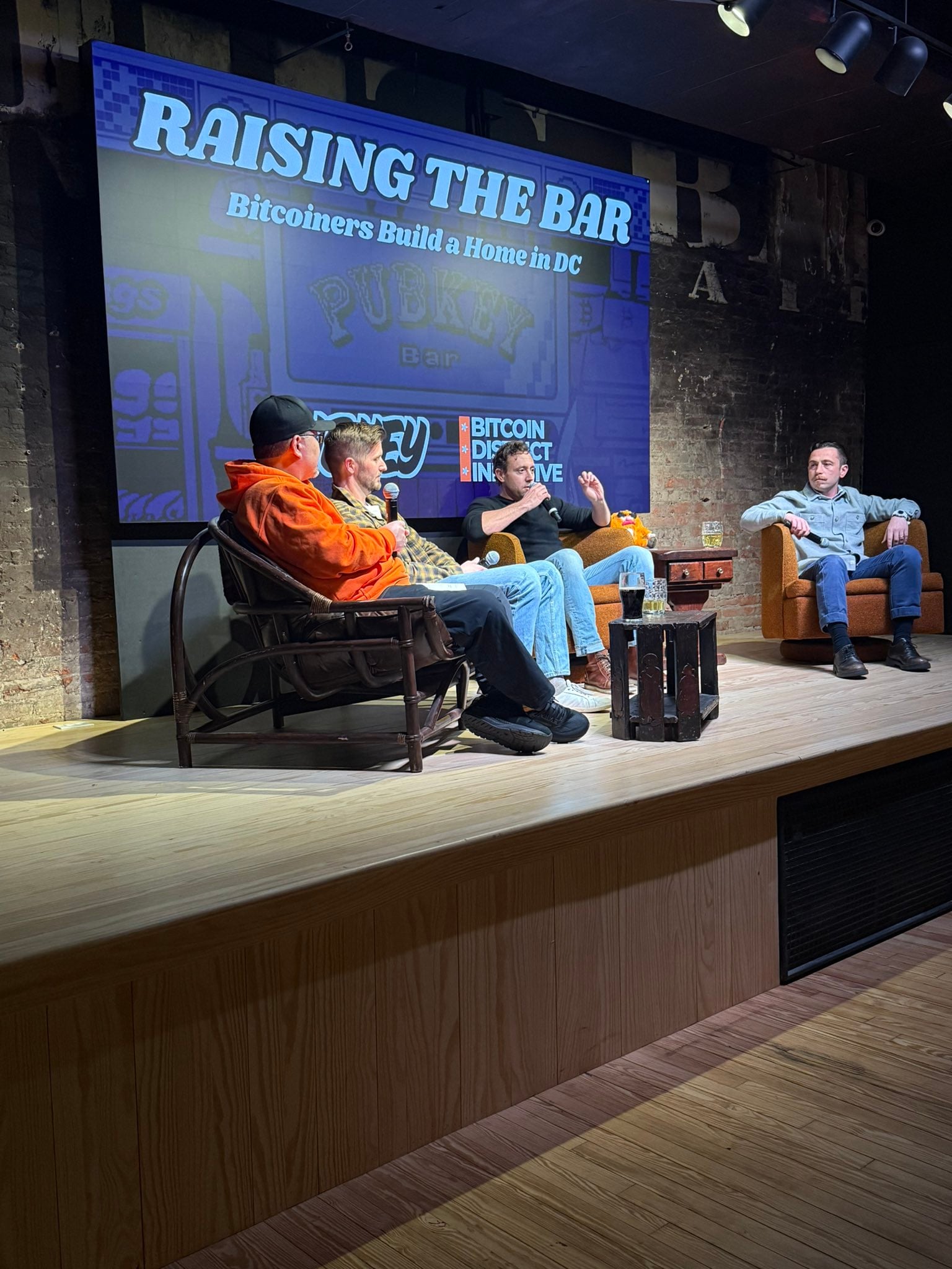 A four-person panel on the PubKey stage under a screen reading “Raising the Bar: Bitcoiners Build a Home in DC.”